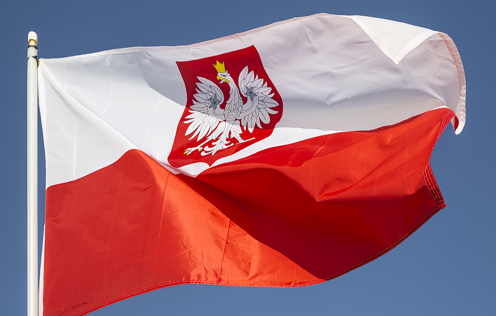 A closeup of the red and white flag of Poland flying in a stiff wind.  This flag is a variant of the usual red and white Polish flag with the national coat of arms in the middle of the white stripe.  It is normally reserved for official use abroad and at sea.